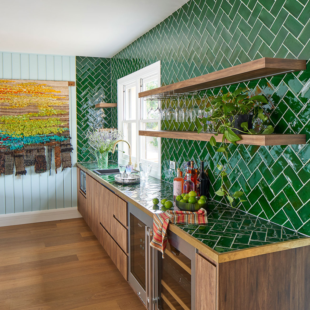 Expansive beach style single-wall wet bar in Central Coast with dark hardwood floors, brown floor, a drop-in sink, brown cabinets, tile benchtops, green splashback, subway tile splashback and green benchtop.