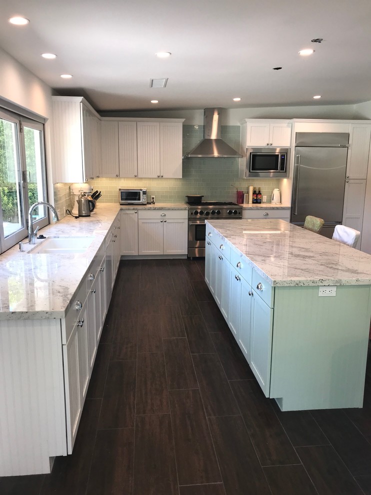 Design ideas for a large transitional l-shaped kitchen in Other with an undermount sink, white cabinets, glass tile splashback, porcelain floors, with island, brown floor, white benchtop, louvered cabinets, quartzite benchtops, grey splashback and stainless steel appliances.