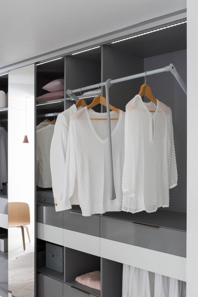 Large contemporary gender-neutral dressing room in Lyon with open cabinets and grey cabinets.