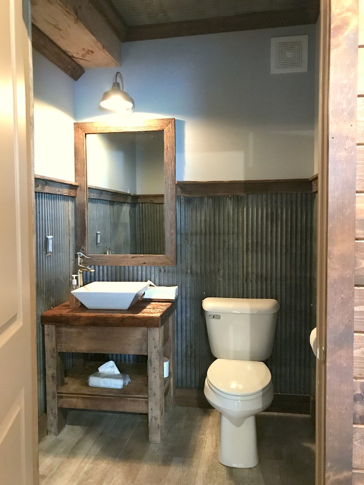 Inspiration for a small country powder room in Other with open cabinets, distressed cabinets, a two-piece toilet, gray tile, metal tile, grey walls, ceramic floors, a vessel sink, zinc benchtops and grey floor.