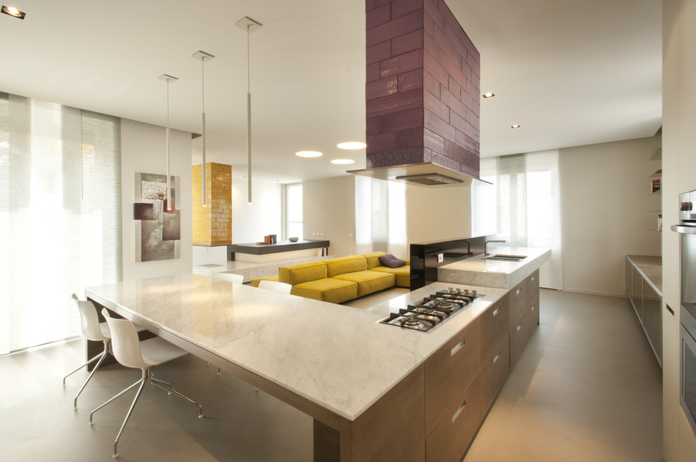 Inspiration for a large contemporary l-shaped open plan kitchen in Milan with a drop-in sink, flat-panel cabinets, light wood cabinets, marble benchtops, black splashback, stainless steel appliances and porcelain floors.