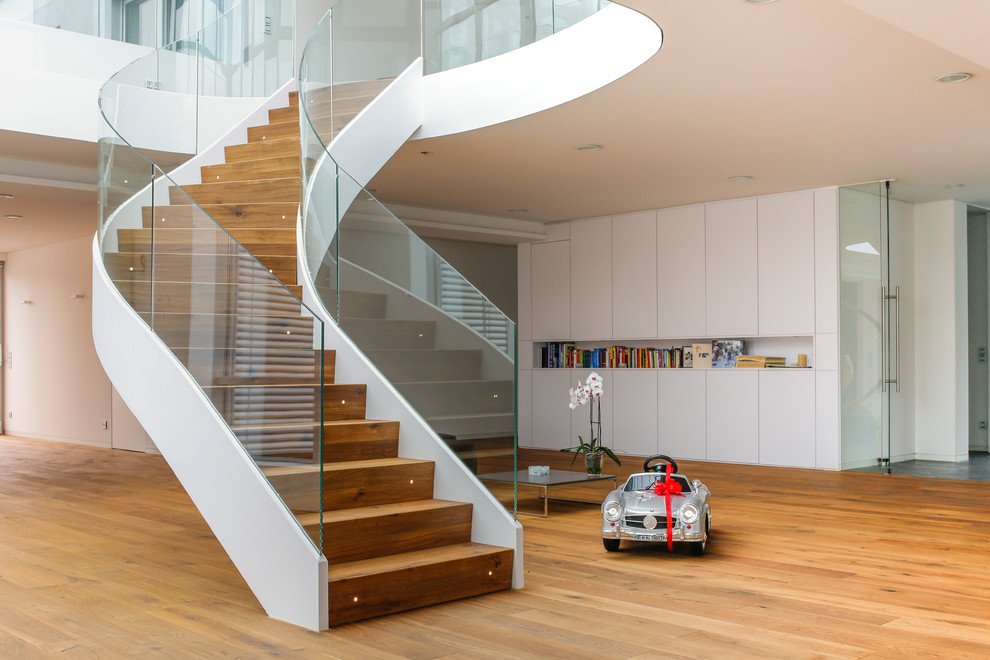 This is an example of a large contemporary wood curved staircase in Munich with wood risers.