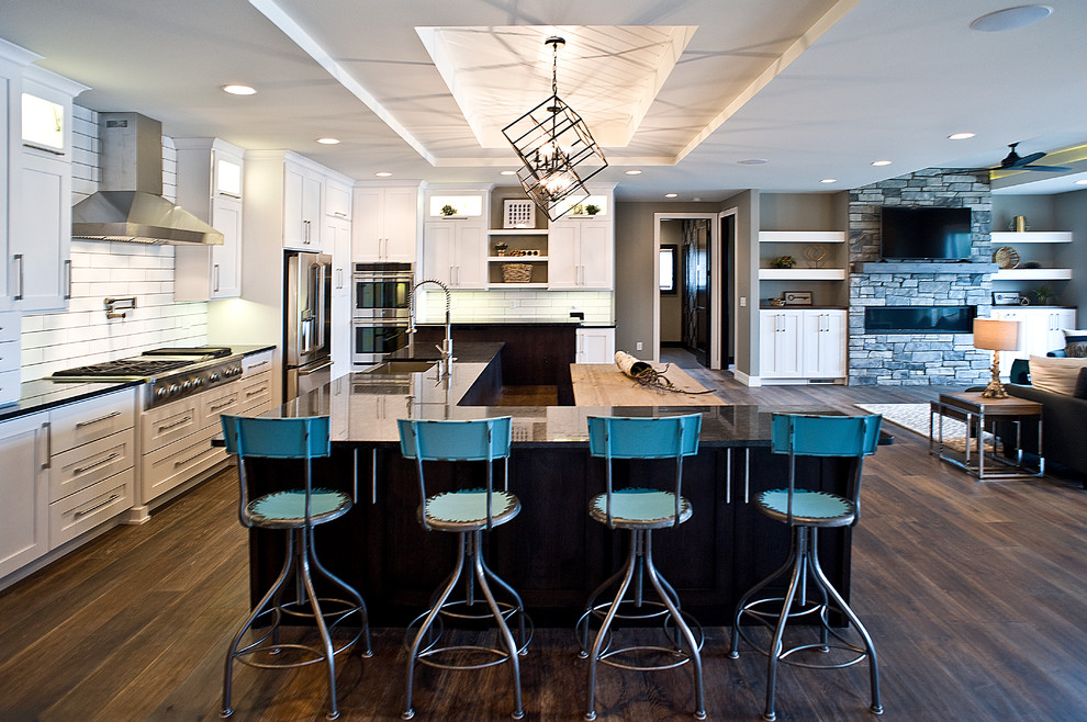 Eat-in kitchen - large transitional l-shaped dark wood floor and brown floor eat-in kitchen idea with an undermount sink, white cabinets, granite countertops, white backsplash, subway tile backsplash, stainless steel appliances, an island and shaker cabinets