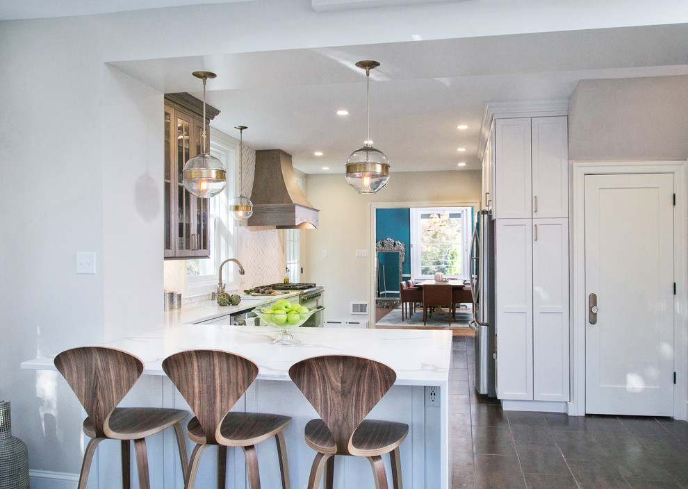 フィラデルフィアの中サイズのトランジショナルスタイルのおしゃれなキッチン (シングルシンク、落し込みパネル扉のキャビネット、白いキャビネット、人工大理石カウンター、白いキッチンパネル、大理石のキッチンパネル、シルバーの調理設備、磁器タイルの床、ベージュの床、白いキッチンカウンター) の写真