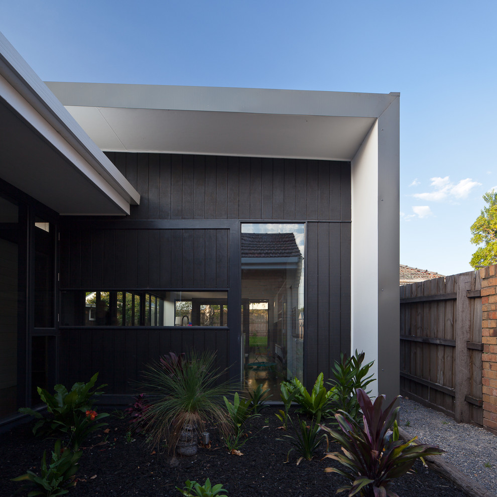 This is an example of a contemporary one-storey black exterior in Melbourne with mixed siding and a flat roof.