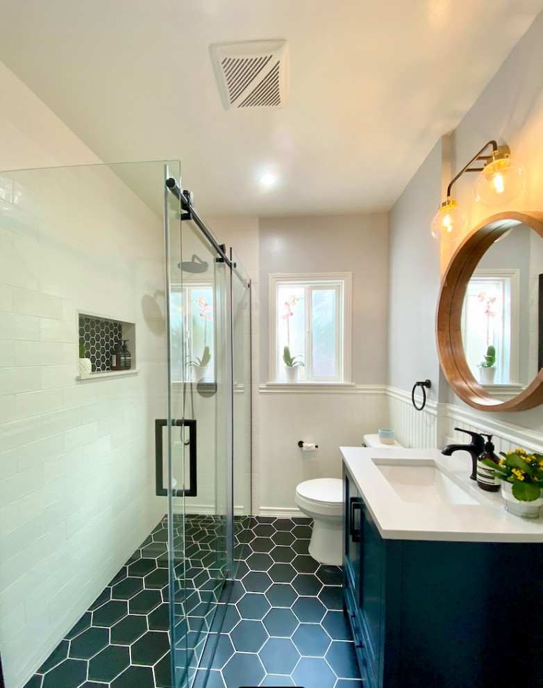 Idéer för ett mellanstort retro vit badrum med dusch, med skåp i shakerstil, blå skåp, en kantlös dusch, en toalettstol med separat cisternkåpa, vit kakel, keramikplattor, vita väggar, klinkergolv i keramik, ett undermonterad handfat, marmorbänkskiva, svart golv och dusch med skjutdörr