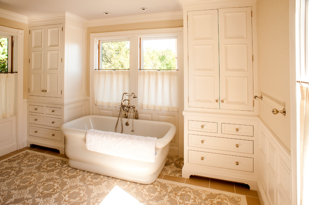 Inspiration for a mid-sized traditional master bathroom in Portland Maine with beaded inset cabinets, white cabinets, a freestanding tub, an alcove shower, a two-piece toilet, beige walls, terra-cotta floors, an undermount sink, marble benchtops, grey floor and a hinged shower door.