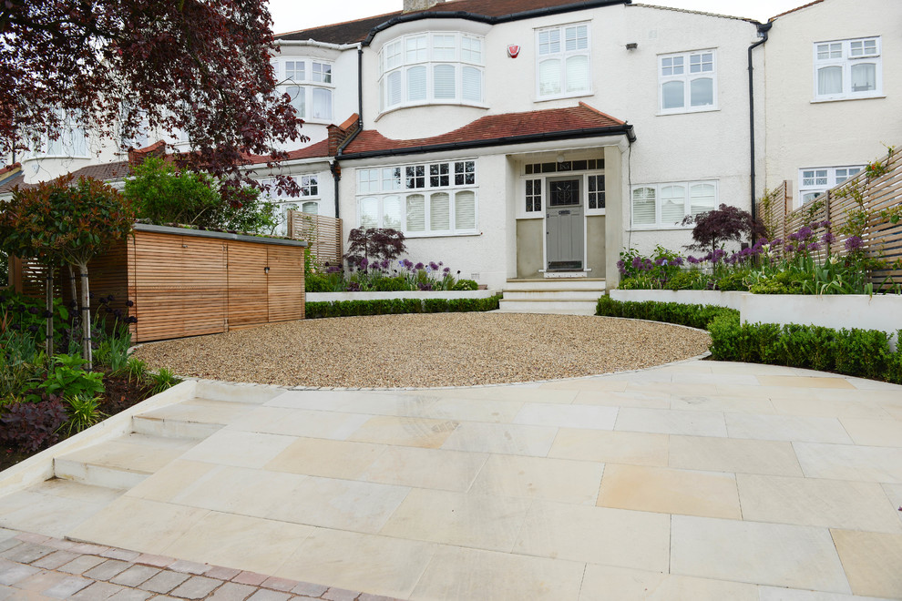 This is an example of a mid-sized contemporary front yard driveway in London with gravel.