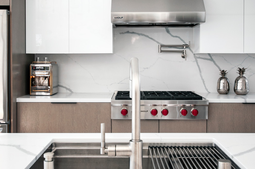 Immagine di una grande cucina contemporanea con lavello a vasca singola, paraspruzzi bianco, paraspruzzi in marmo, elettrodomestici in acciaio inossidabile, pavimento in legno massello medio e top bianco