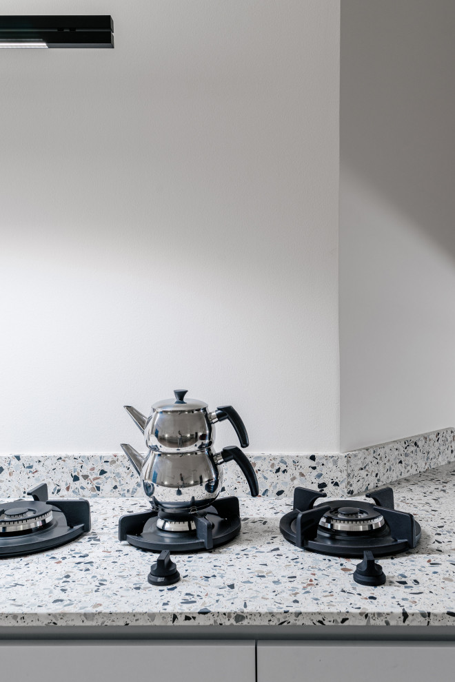 Diseño de cocina minimalista con puertas de armario grises, encimera de terrazo y encimeras blancas