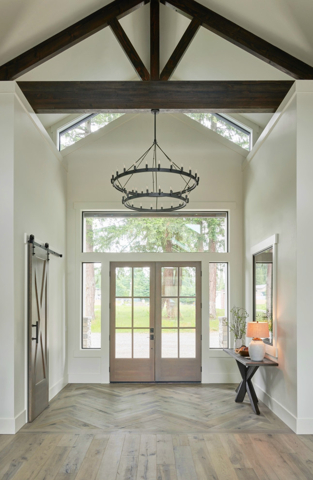 Large country foyer in Seattle with white walls, light hardwood floors, a double front door, a glass front door, brown floor and exposed beam.
