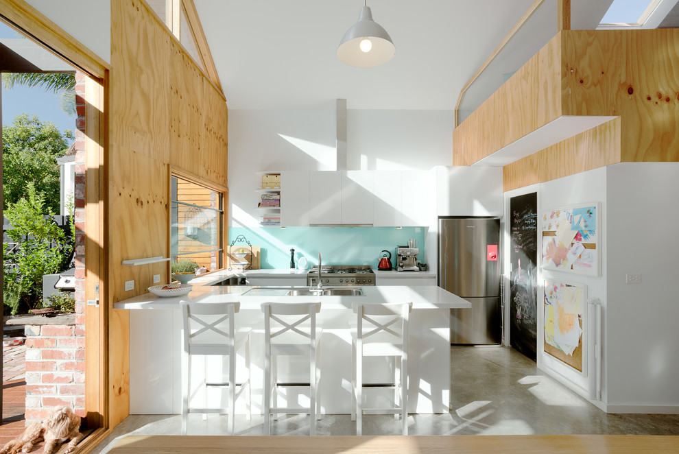 Design ideas for a mid-sized contemporary u-shaped eat-in kitchen in Melbourne with a double-bowl sink, flat-panel cabinets, white cabinets, blue splashback, glass sheet splashback, stainless steel appliances, concrete floors and no island.