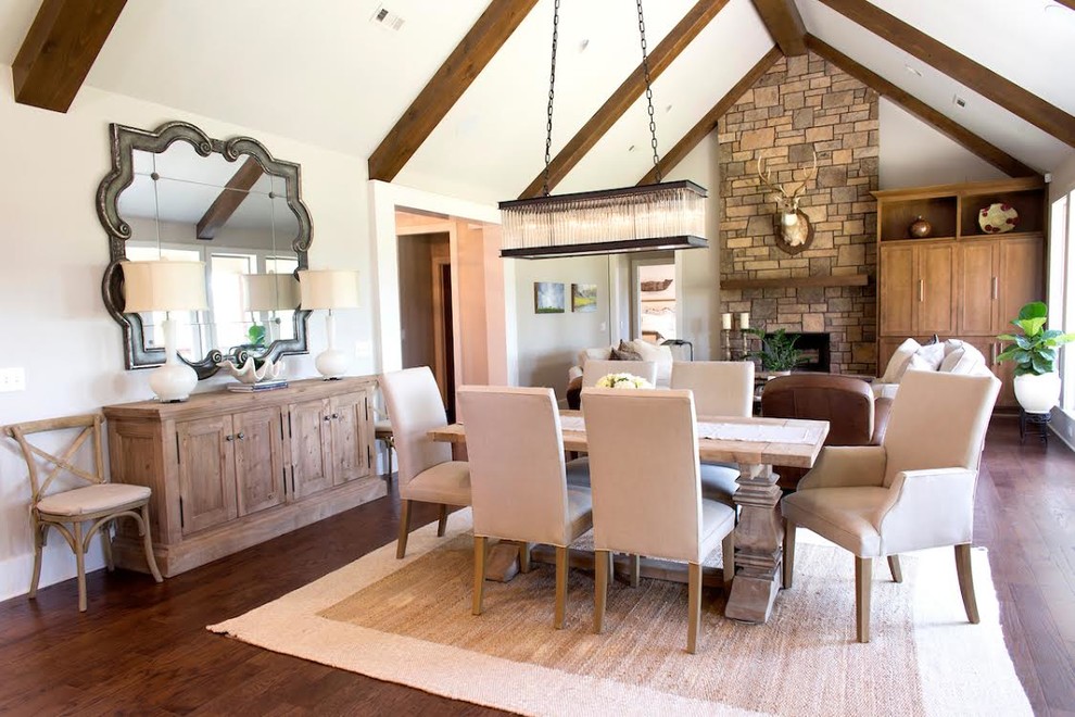 Photo of a mid-sized country open plan dining in Other with white walls, dark hardwood floors, a standard fireplace and a stone fireplace surround.