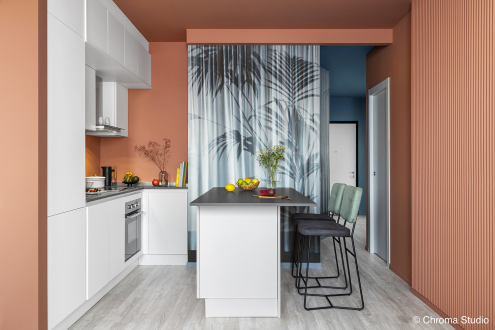Foto på ett mellanstort funkis grå kök, med en nedsänkt diskho, släta luckor, vita skåp, stänkskydd med metallisk yta, rostfria vitvaror, ljust trägolv, en köksö och vitt golv