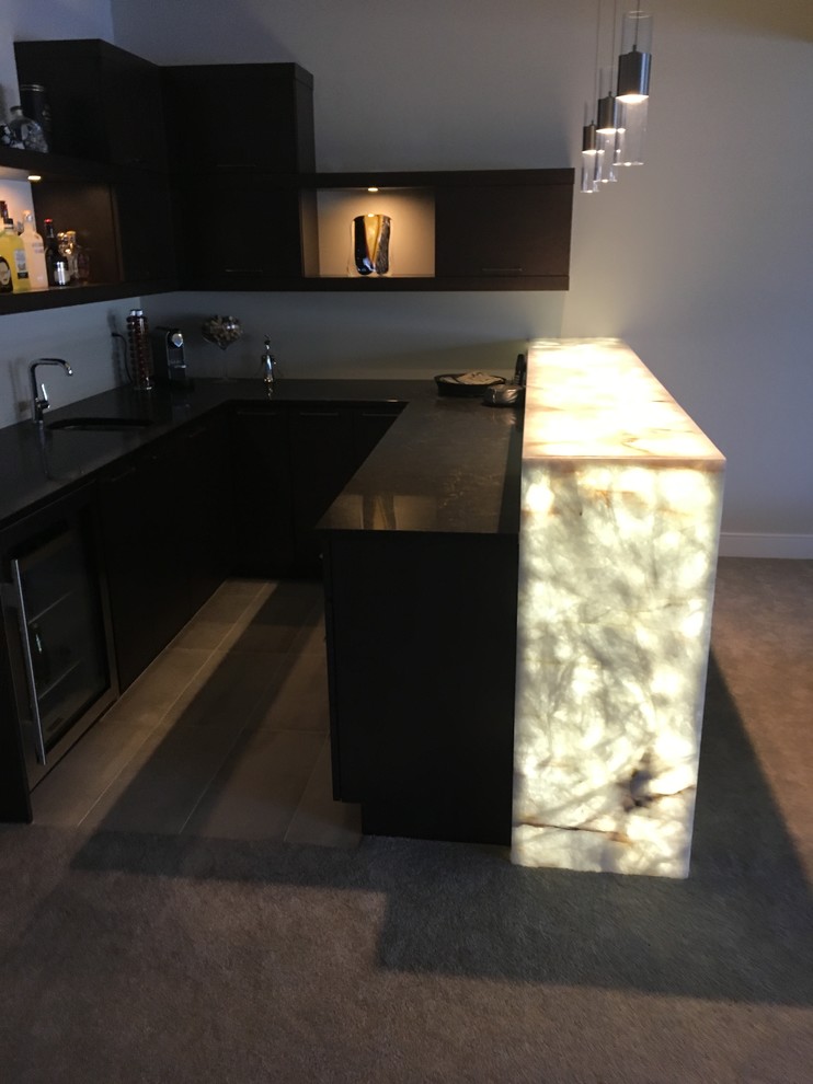 This is an example of a large contemporary u-shaped wet bar in Edmonton with flat-panel cabinets, dark wood cabinets and quartzite benchtops.