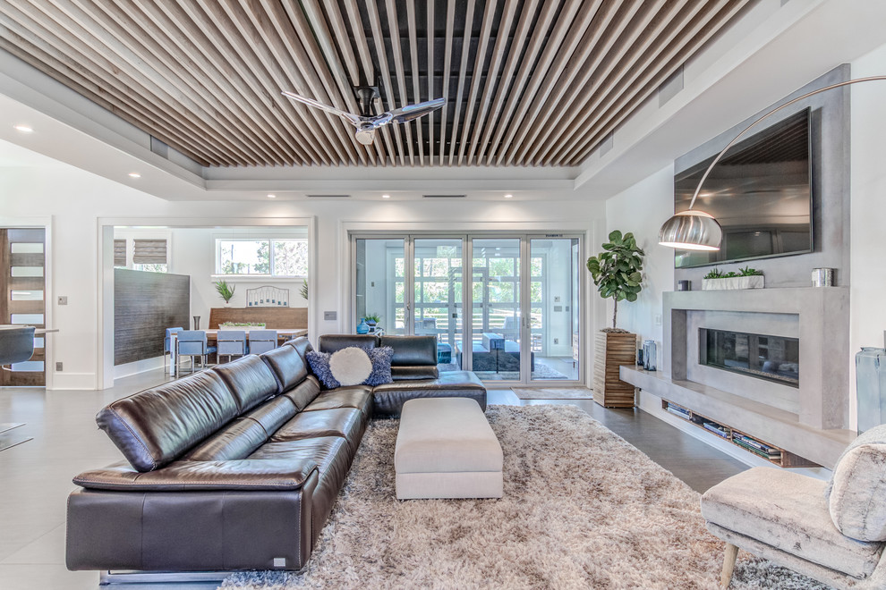 Expansive contemporary open concept living room in Wilmington with a concrete fireplace surround, grey floor, white walls and a ribbon fireplace.