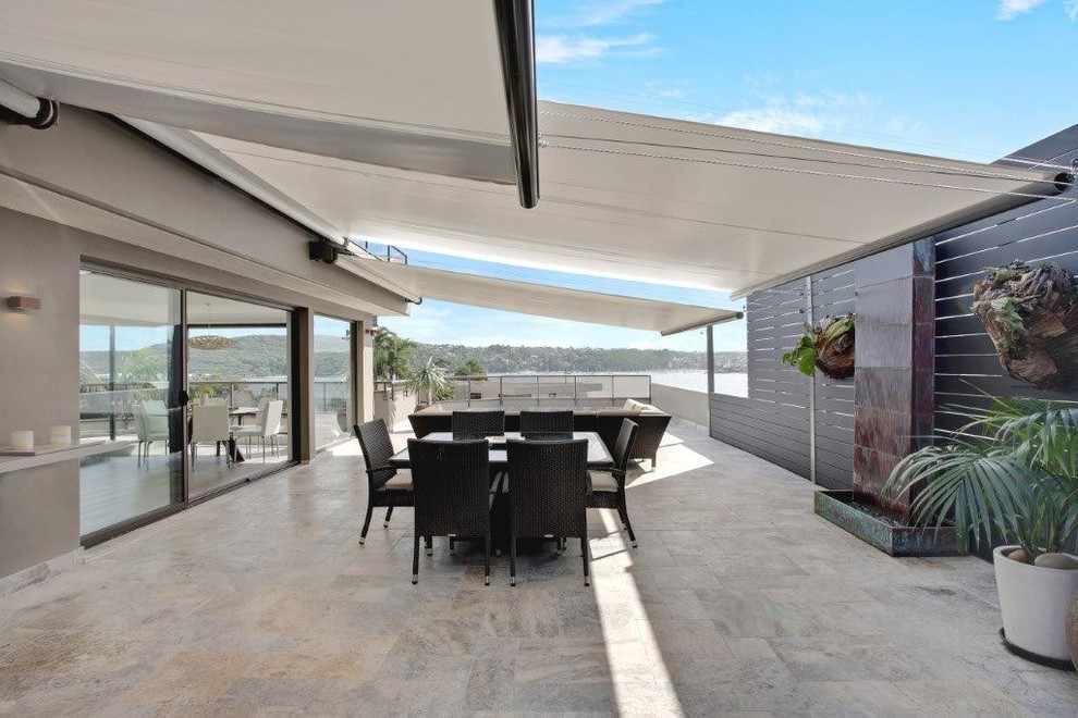 Photo of a large contemporary side yard patio in Sydney with tile and an awning.