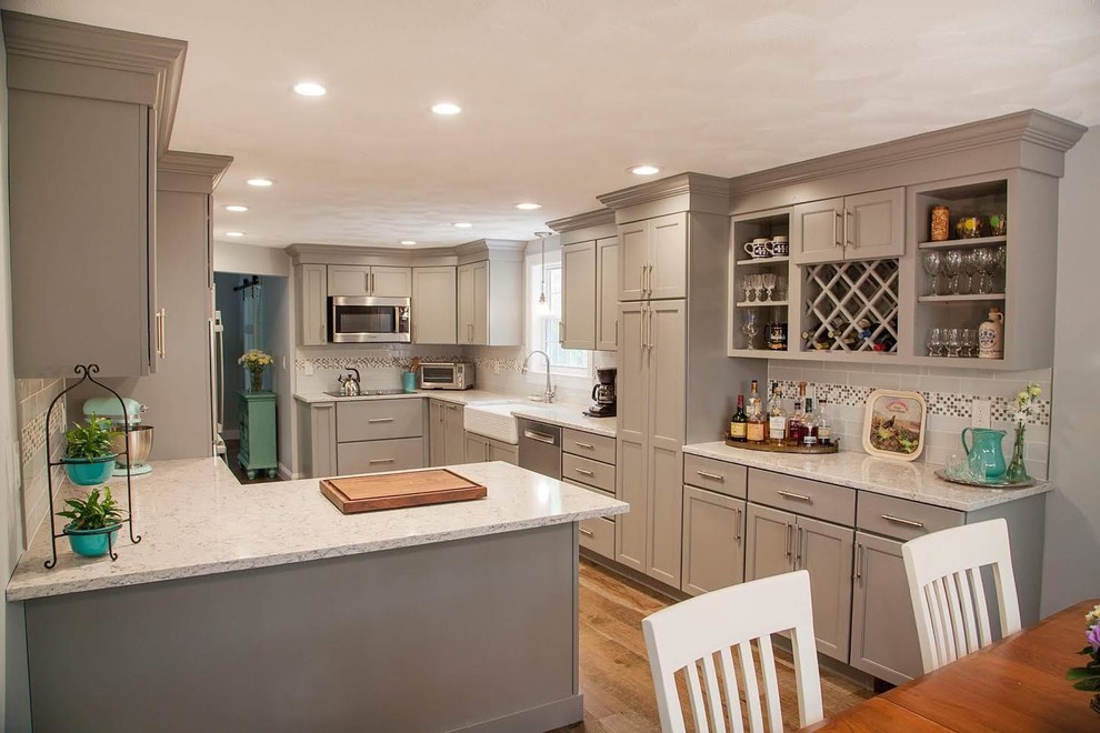 This is an example of a large transitional u-shaped eat-in kitchen in Boston with a farmhouse sink, recessed-panel cabinets, grey cabinets, quartz benchtops, multi-coloured splashback, mosaic tile splashback, stainless steel appliances, medium hardwood floors, no island and brown floor.