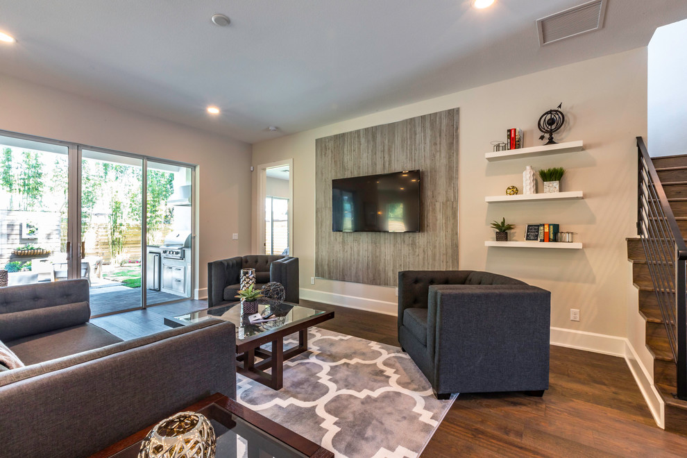This is an example of a large country open concept living room in Orlando with grey walls, dark hardwood floors, a wall-mounted tv and brown floor.