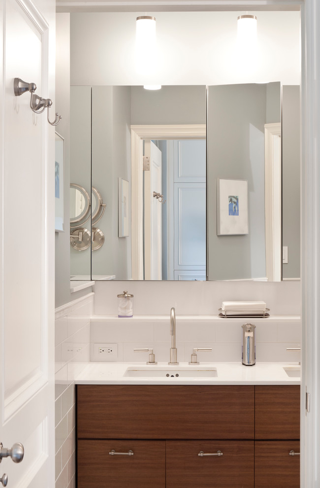 Mid-sized transitional master bathroom in New York with flat-panel cabinets, medium wood cabinets, an alcove shower, a wall-mount toilet, white tile, stone tile, white walls, mosaic tile floors, an undermount sink, glass benchtops, grey floor and a hinged shower door.