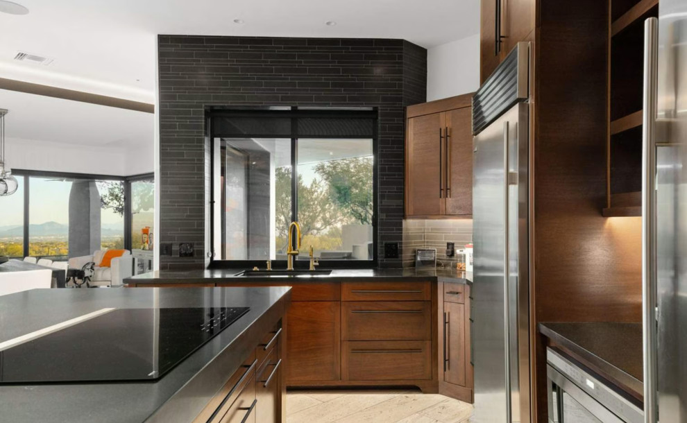 Inspiration for a large modern porcelain tile, brown floor and tray ceiling eat-in kitchen remodel with an undermount sink, shaker cabinets, medium tone wood cabinets, black backsplash, mosaic tile backsplash, stainless steel appliances, an island and black countertops