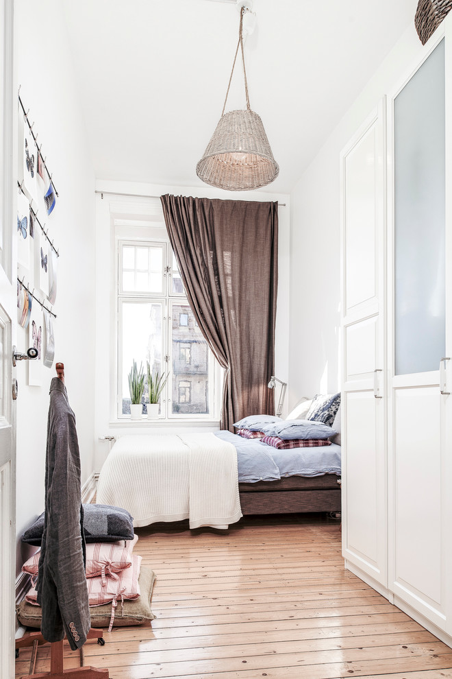 Design ideas for a large scandinavian master bedroom in Gothenburg with white walls and light hardwood floors.