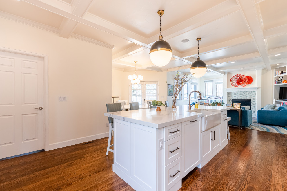 Inspiration for an expansive beach style l-shaped kitchen/diner in Denver with a belfast sink, shaker cabinets, white cabinets, quartz worktops, multi-coloured splashback, ceramic splashback, stainless steel appliances, medium hardwood flooring, an island, white worktops and exposed beams.