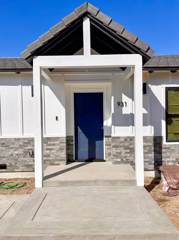Example of a cottage concrete floor and vaulted ceiling single front door design in Los Angeles with white walls and a blue front door