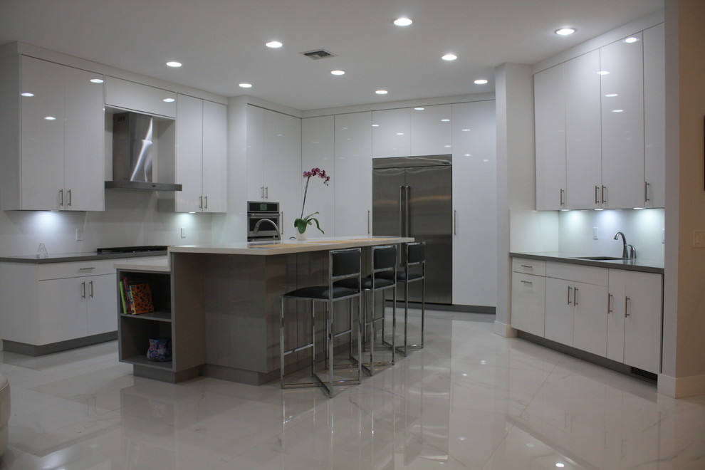 Large contemporary l-shaped separate kitchen in Miami with stone slab splashback, stainless steel appliances, white floor, an undermount sink, flat-panel cabinets, white cabinets, quartz benchtops, white splashback, marble floors, with island and white benchtop.