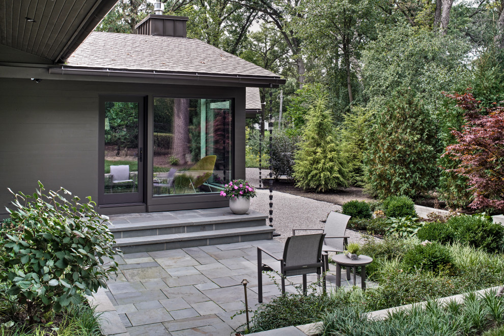 Immagine di un patio o portico moderno di medie dimensioni e dietro casa con un giardino in vaso e pavimentazioni in pietra naturale