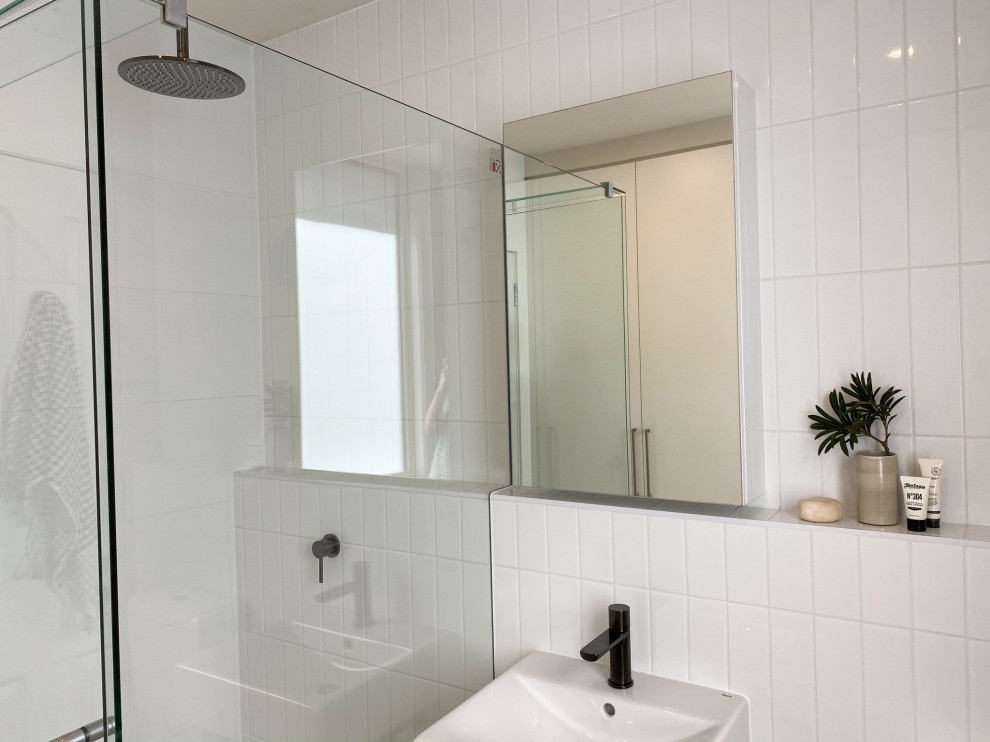 Inspiration for a small contemporary bathroom in Melbourne with a corner shower, white tiles, metro tiles, porcelain flooring, a wall-mounted sink, brown floors, a hinged door and a single sink.