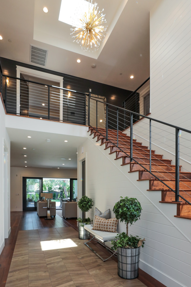 Exemple d'un grand escalier droit tendance avec des marches en bois, des contremarches en bois et un garde-corps en câble.
