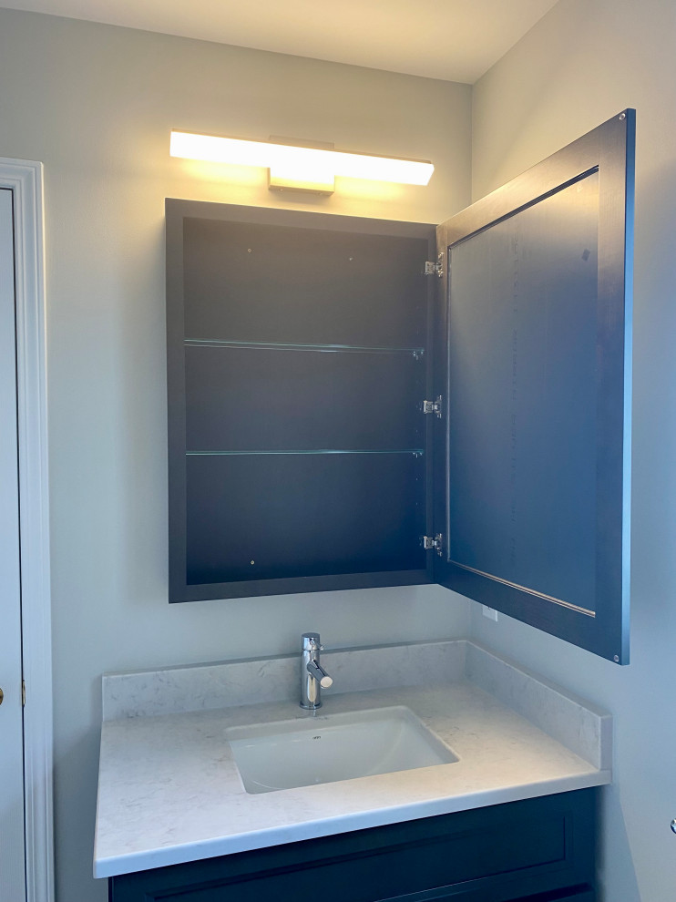 Transitional 3/4 porcelain tile, gray floor and single-sink bathroom photo with recessed-panel cabinets, a one-piece toilet, gray walls, an undermount sink, quartzite countertops, white countertops and a built-in vanity