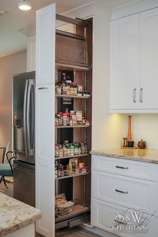 Inspiration for a mid-sized transitional galley porcelain tile eat-in kitchen remodel in Tampa with a farmhouse sink, flat-panel cabinets, white cabinets, quartz countertops, white backsplash, subway tile backsplash, stainless steel appliances and a peninsula