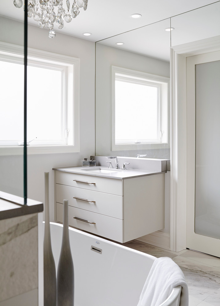 Inspiration for a contemporary master bathroom in Toronto with flat-panel cabinets, white cabinets, a freestanding tub, a curbless shower, gray tile, white tile, stone tile and marble floors.