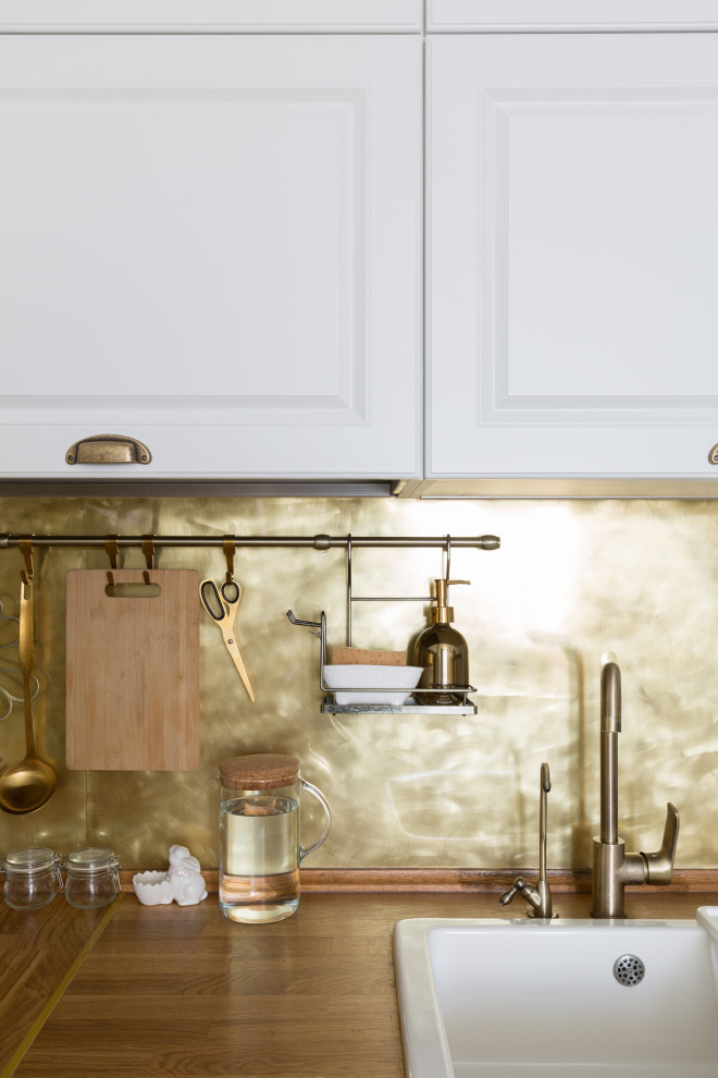 Eklektisk inredning av ett litet brun brunt kök, med en rustik diskho, träbänkskiva, stänkskydd med metallisk yta, stänkskydd i metallkakel, vita vitvaror, laminatgolv och brunt golv