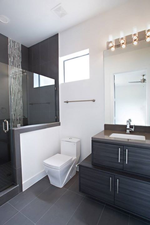 This is an example of a small contemporary 3/4 bathroom in Houston with an undermount sink, flat-panel cabinets, grey cabinets, an alcove shower, a one-piece toilet, gray tile and white walls.