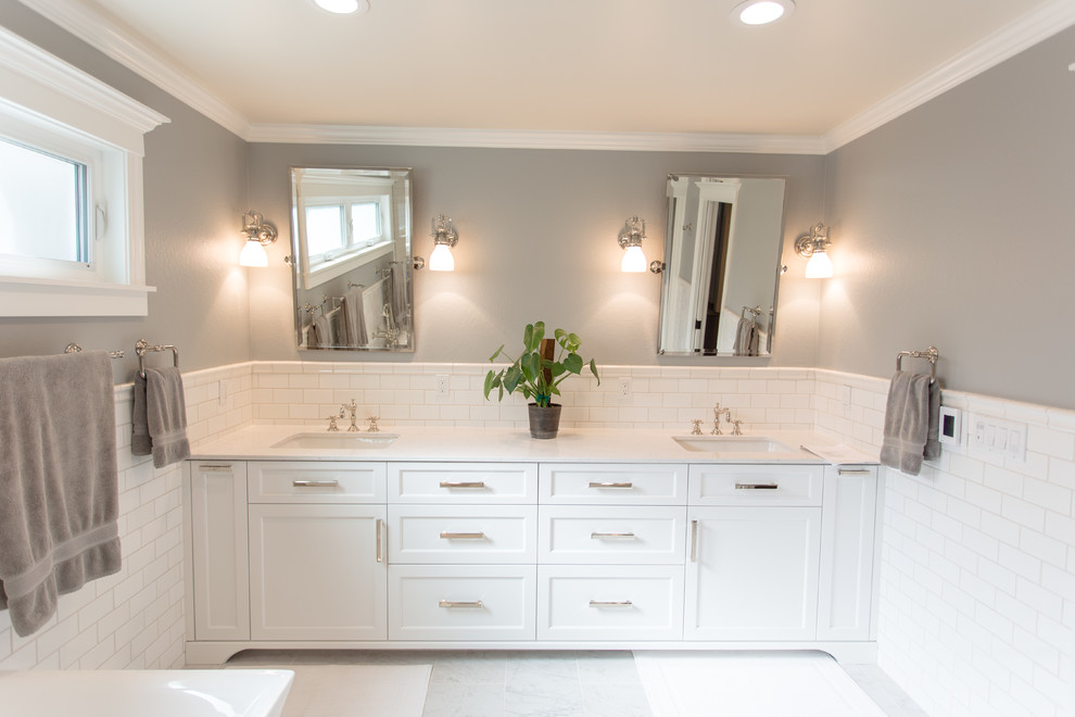 This is an example of a country bathroom in San Francisco with shaker cabinets, white cabinets, a freestanding tub, a double shower, a two-piece toilet, gray tile, ceramic tile, grey walls, ceramic floors, an undermount sink, engineered quartz benchtops, white floor and a hinged shower door.