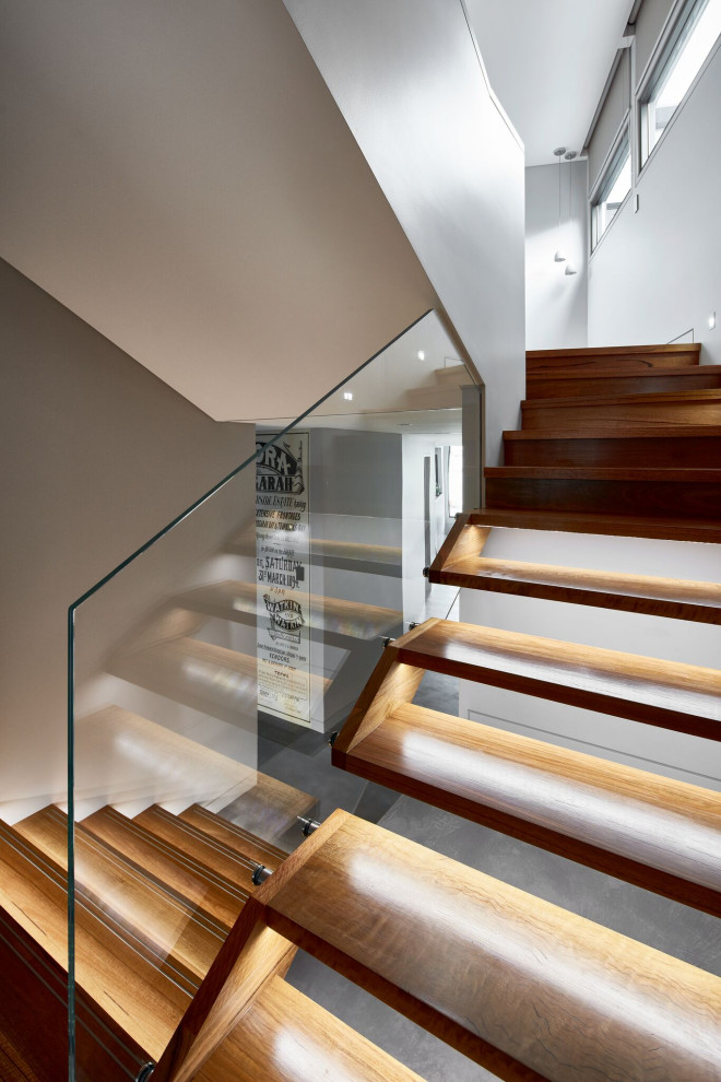 Photo of a contemporary wood floating staircase in Sydney with open risers and glass railing.