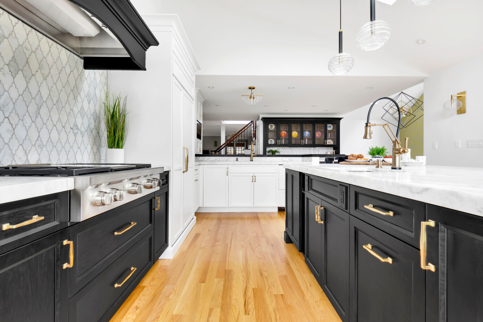 Eat-in kitchen - large transitional l-shaped light wood floor, beige floor and vaulted ceiling eat-in kitchen idea in New York with an undermount sink, shaker cabinets, black cabinets, quartz countertops, white backsplash, marble backsplash, paneled appliances, an island and white countertops