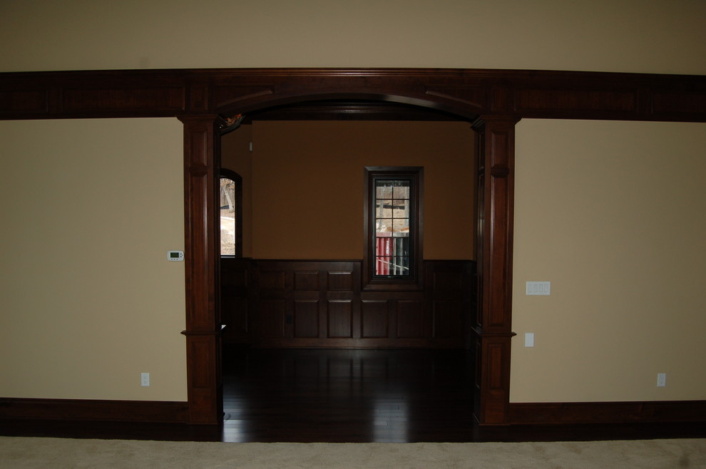 Photo of an expansive midcentury hallway in Milwaukee with brown walls and dark hardwood floors.