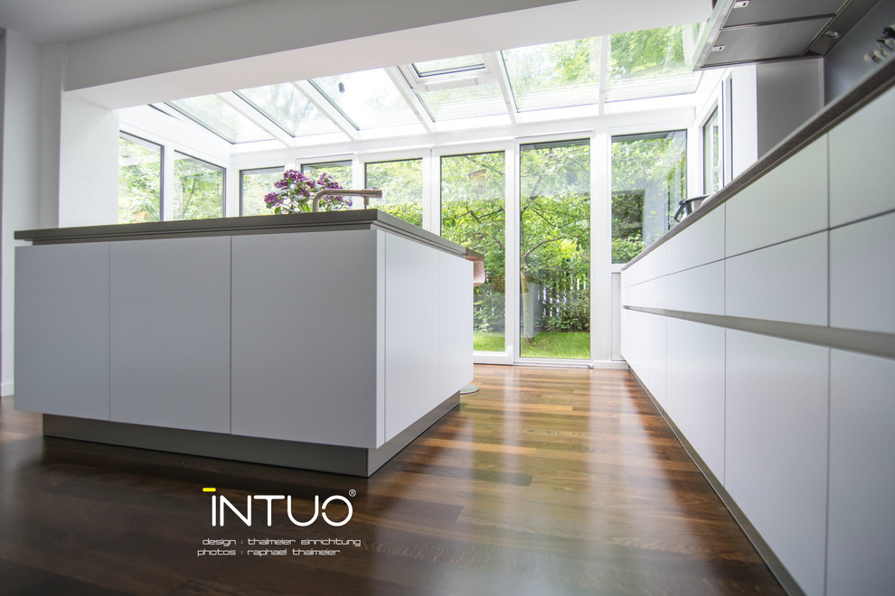 Design ideas for a mid-sized contemporary kitchen in Surrey with an undermount sink, flat-panel cabinets, white cabinets, solid surface benchtops, stainless steel appliances, dark hardwood floors and with island.
