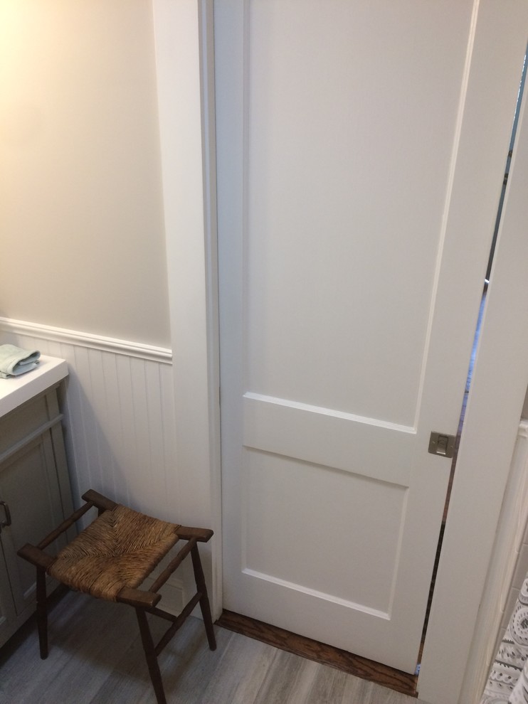 Small transitional powder room in Boston with recessed-panel cabinets, grey cabinets, a two-piece toilet, grey walls, porcelain floors, an integrated sink, solid surface benchtops and grey floor.