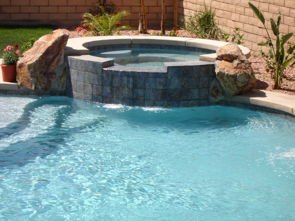 This is an example of a small tropical backyard round natural pool in Los Angeles with a hot tub and decking.