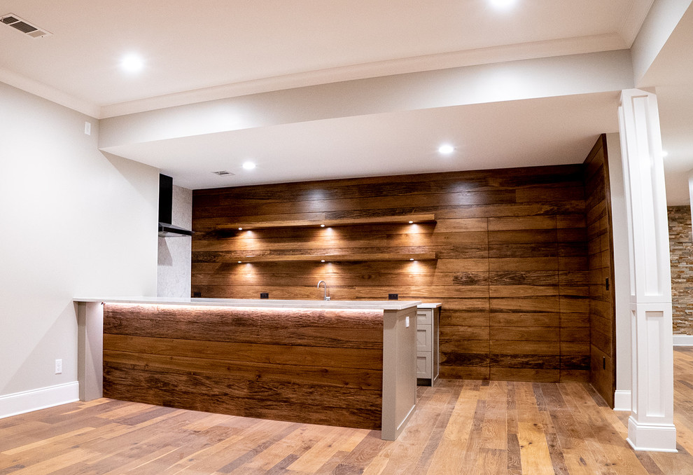 Mid-sized arts and crafts l-shaped seated home bar in Atlanta with an undermount sink, shaker cabinets, grey cabinets, quartz benchtops, brown splashback, timber splashback, medium hardwood floors, brown floor and white benchtop.