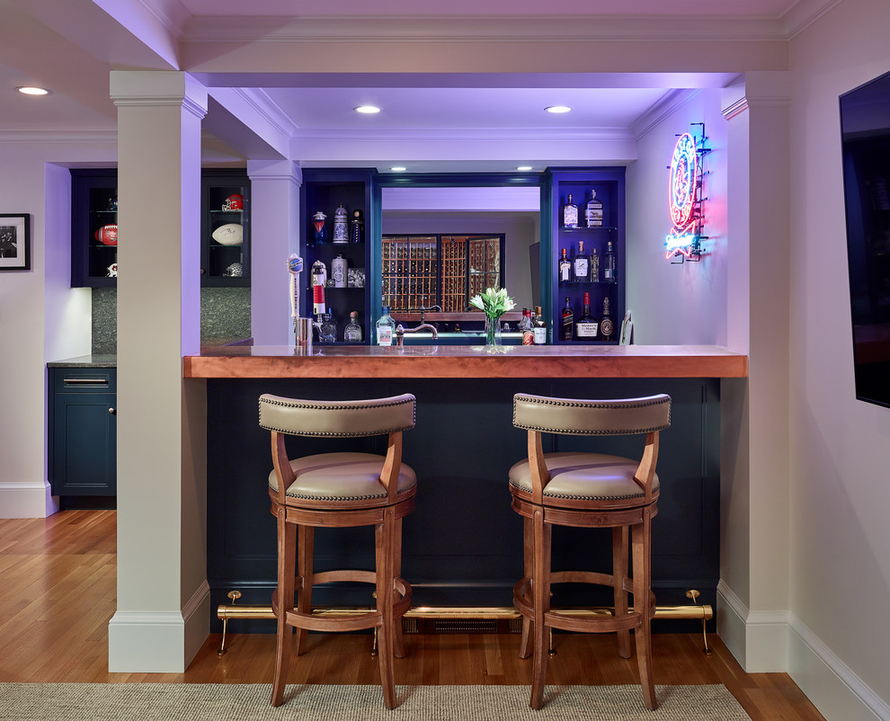 This is an example of a large traditional galley seated home bar in Boston with an undermount sink, shaker cabinets, blue cabinets, copper benchtops, mirror splashback, medium hardwood floors, brown floor and orange benchtop.