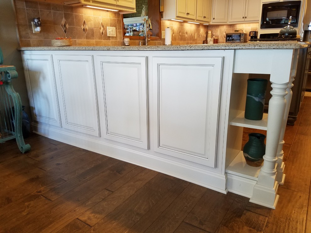 Photo of a mid-sized traditional u-shaped separate kitchen in Charlotte with an undermount sink, raised-panel cabinets, white cabinets, quartz benchtops, brown splashback, ceramic splashback, stainless steel appliances, medium hardwood floors and with island.