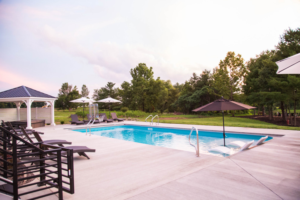 Diseño de piscinas y jacuzzis de estilo americano grandes rectangulares en patio trasero con losas de hormigón