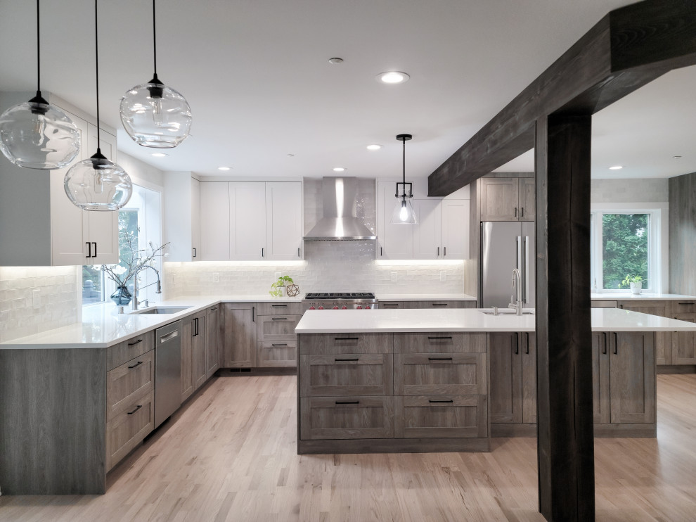 Example of a large transitional l-shaped light wood floor, beige floor and exposed beam eat-in kitchen design in Seattle with a single-bowl sink, shaker cabinets, medium tone wood cabinets, quartz countertops, white backsplash, ceramic backsplash, stainless steel appliances, an island and white countertops