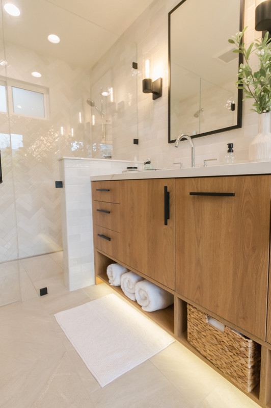 This is an example of a large modern ensuite bathroom in San Francisco with flat-panel cabinets, brown cabinets, a freestanding bath, a built-in shower, grey tiles, porcelain flooring, a submerged sink, solid surface worktops, grey floors, a hinged door, a shower bench, double sinks and a freestanding vanity unit.